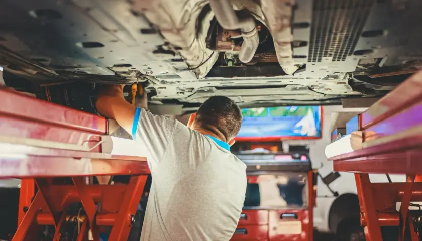 Mechanik pracuje pod samochodem, sprawdzając sworzeń wahacza.
