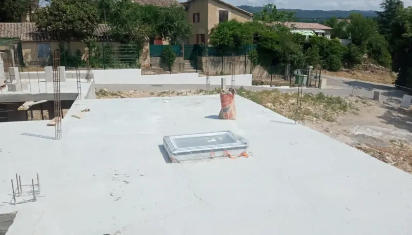Chantier de construction avec dalle béton fraîchement coulée. Sac de ciment à proximité, peut-être pour estimer le prix dalle béton m2.