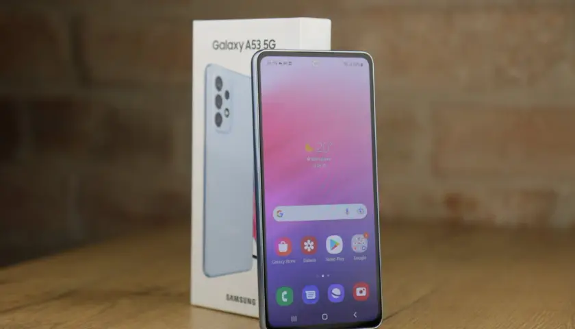 Jasnoniebieski Samsung A53 5G, model z 2022 roku, obok swojego pudełka. Ekran pokazuje pogodę i ikony aplikacji.