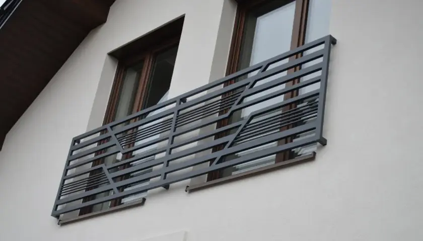 Nowoczesne balkony francuskie z metalową, geometryczną balustradą zdobią elewację domu.