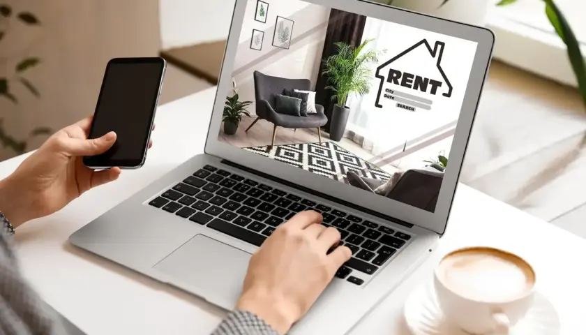 Szukasz mieszkania? Na co zwrócić uwagę przy wynajmie? Laptop pokazuje ofertę, a telefon jest pod ręką.