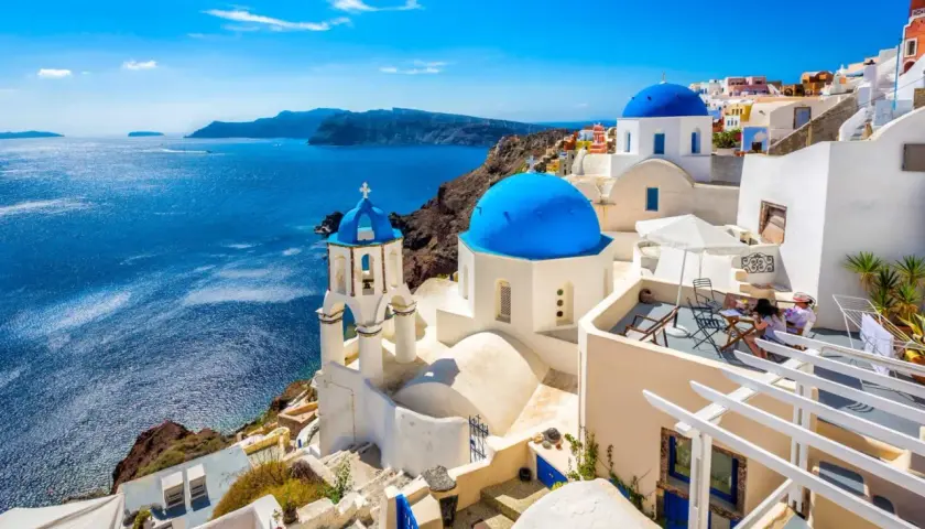 Białe domy z niebieskimi kopułami na tle morza. Widok na Santorini, jedne z najpiękniejszych wysp greckich.