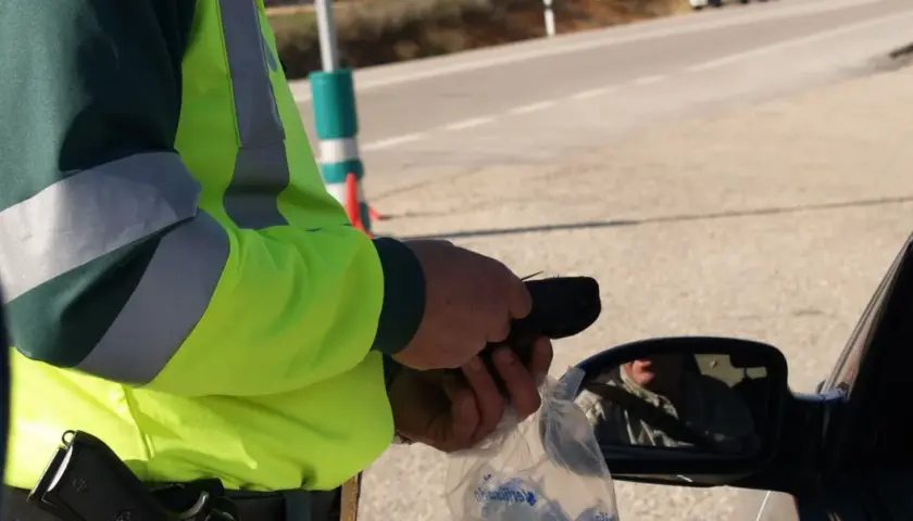 Policjant w kamizelce odblaskowej mierzy kierowcy trzeźwość. W Polsce obowiązują surowe przepisy dotyczące tego, ile promili można mieć we krwi.