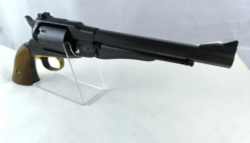 Czarny rewolwer Uberti Remington 1858 z drewnianą rękojeścią, prezentowany na przezroczystym stojaku.