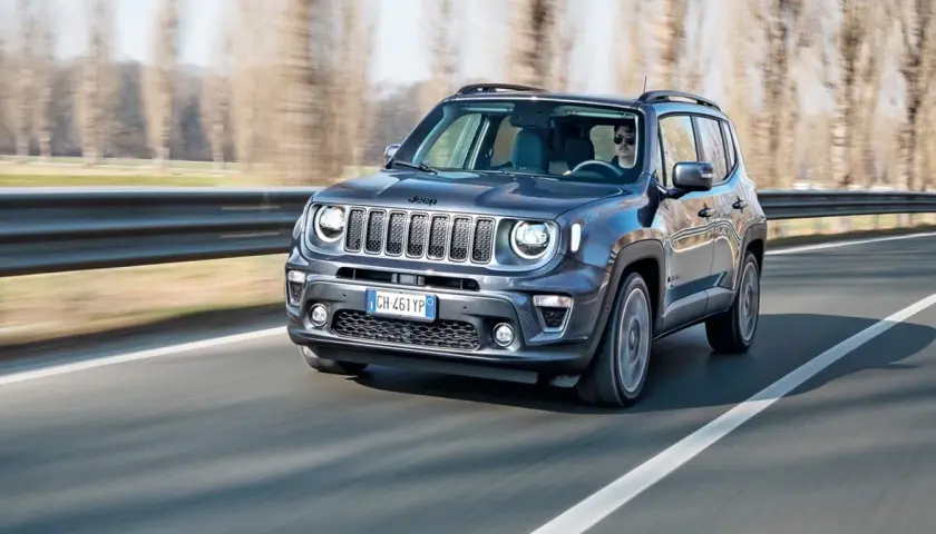 Ciemnoszary Jeep Renegade Hybrid jedzie po drodze, za kierownicą siedzi mężczyzna w okularach.