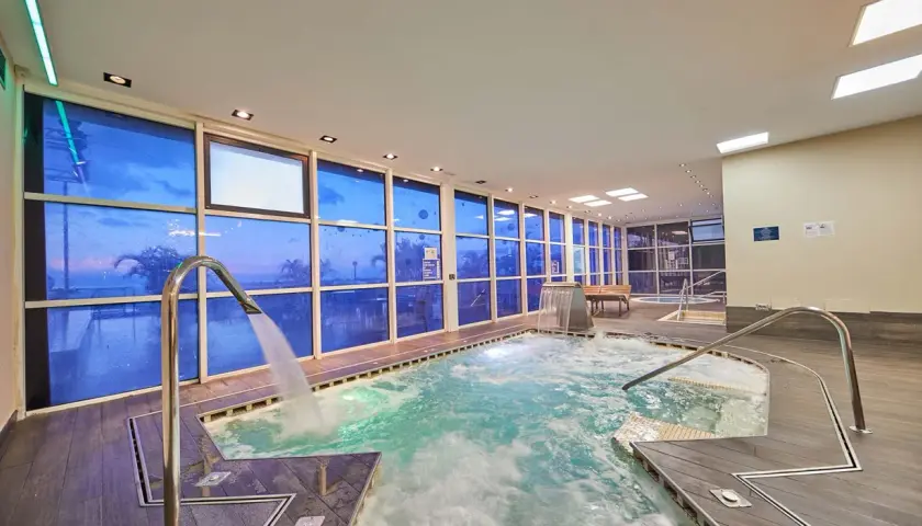 Piscina interior con ventanas azules que reflejan el cielo, cascadas y chorros de agua. Un lugar perfecto para relajarse, como si estuvieras en un spa de tui blue los gigantes.
