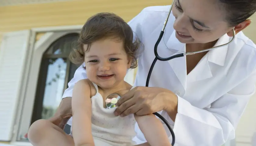 Medico ascolta il cuore di un bambino con uno stetoscopio. Un soffio al cuore cos'è? La visita medica rassicura.