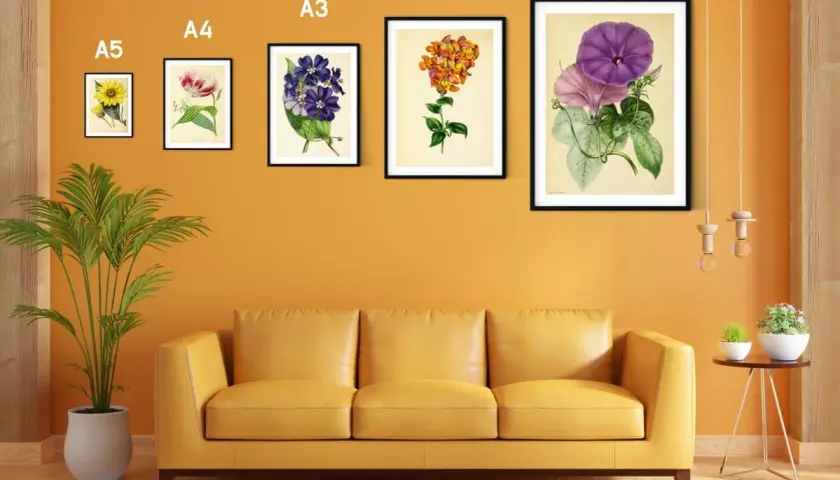 Un sofá amarillo bajo un marco din A3 con flores moradas y rosadas.