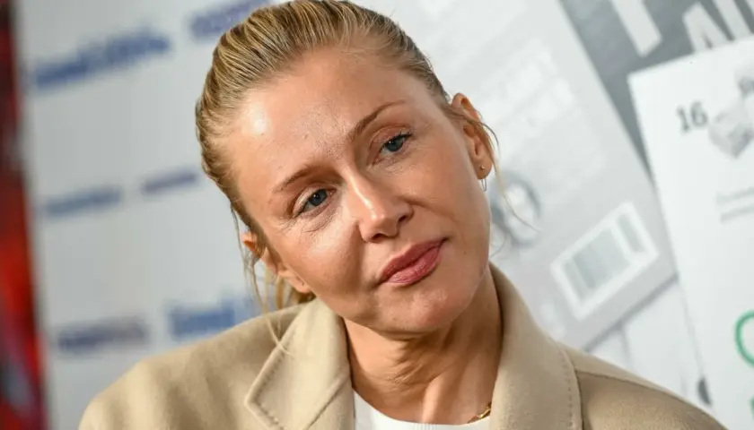 Katarzyna Warnke w beżowym płaszczu, z włosami upiętymi do tyłu. Aktorka znana z wielu polskich filmów.