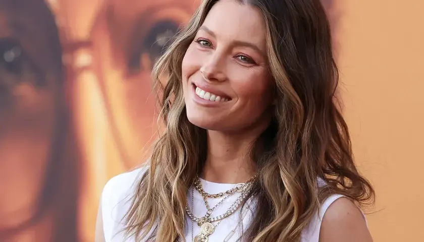 Jessica Biel sonríe con su pelo liso y mechas balayage, luciendo un collar de varias cadenas.