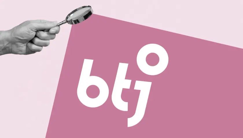 En hand håller ett förstoringsglas över logotypen "btj". Symboliserar granskning och djupgående btj recensioner.