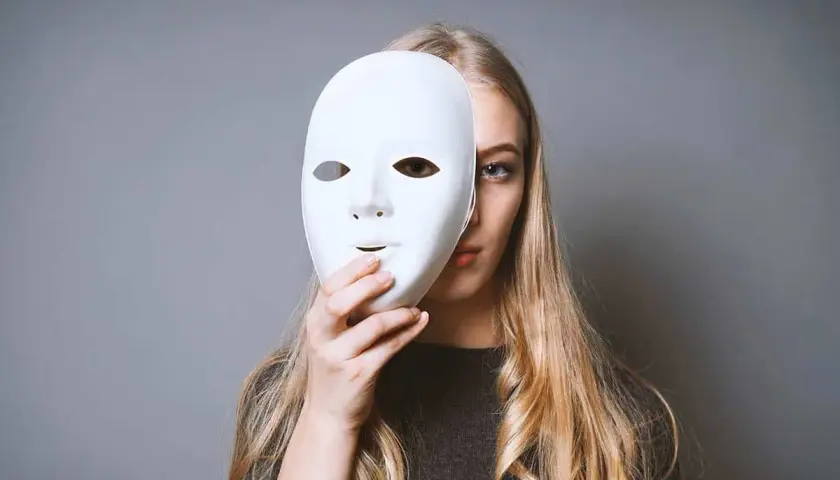 Ragazza bionda con maschera bianca, un'espressione che evoca il disturbo istrionico di personalità.