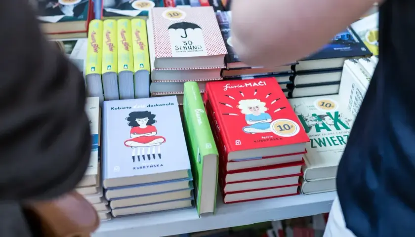 Na półce stoją książki, m.in. "Kobieta dość doskonała" i "Furia maći". Zastanawiasz się, ile zarabia autor na jednej sprzedanej książce procenty i tantiemy?