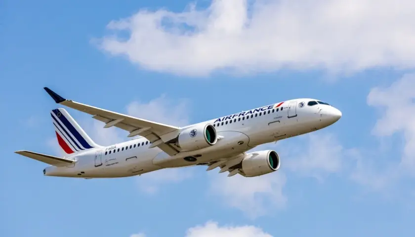 Airbus A220-300 linii Air France wzbija się w błękitne niebo z białymi chmurami.