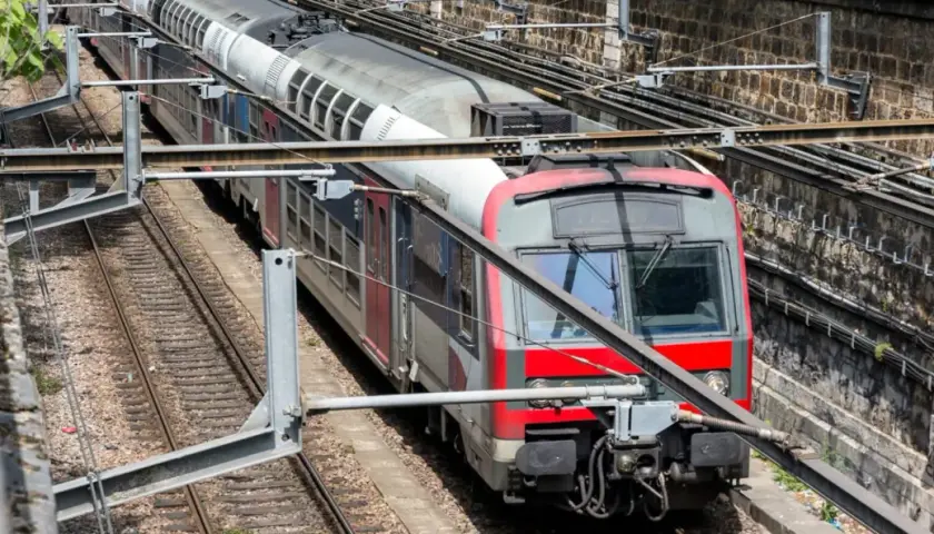 Pociąg RER A w Paryżu na torach, z widocznymi elementami infrastruktury kolejowej.