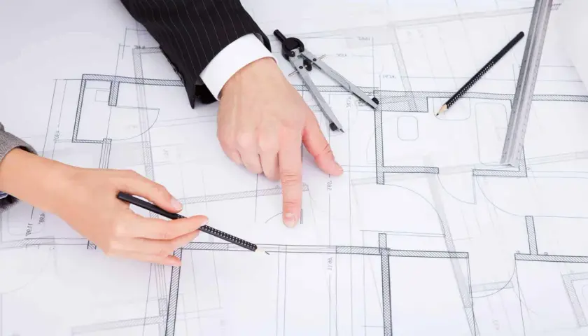 Dwie osoby analizują projekt budowlany, dyskutując, jak zaznaczyć zmiany nieistotne w projekcie.