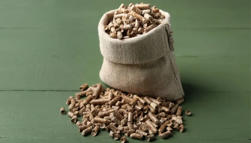 Worek z pelletem na zielonym tle. Zastanawiasz się, ile waży worek pelletu?