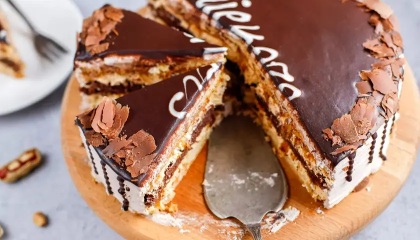 Pyszny tort snickers z czekoladą i orzeszkami, pokrojony na kawałki, gotowy do podania.