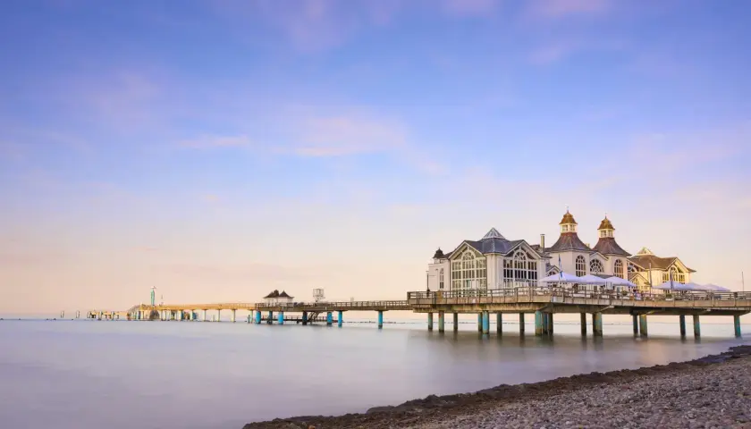 Die Seebrücke im Ostseebad Sellin erstreckt sich ins ruhige Meer. Ein malerischer Anblick bei Sonnenuntergang.