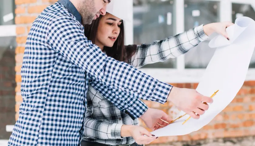 Pareja revisa planos de construcción. Saben qué se necesita para tasar una vivienda, analizando cada detalle.