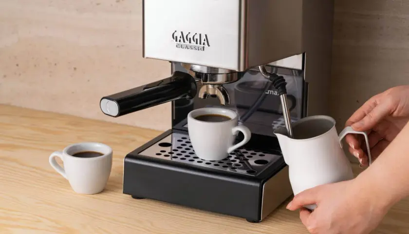 Jaka kawa do ekspresu kolbowego? Świeżo zaparzony espresso w filiżance, obok dzbanek do mleka.