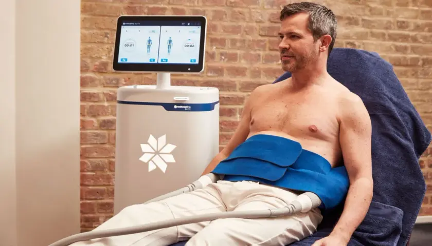Man får behandling med CoolSculpting för att reducera fett på magen.