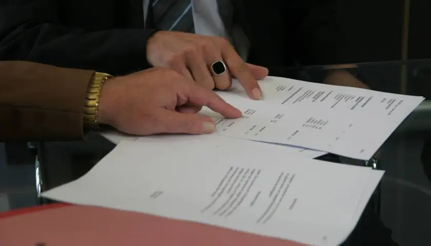Dwaj mężczyźni analizują dokumenty, jeden wskazuje palcem na wypowiedzenie umowy najmu wzór przez wynajmującego.