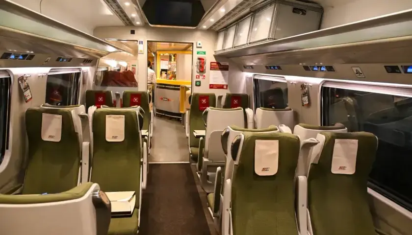 Wnętrze wagonu PKP Intercity. Zielone siedzenia bez gwarancji miejsca do siedzenia czekają na pasażerów.