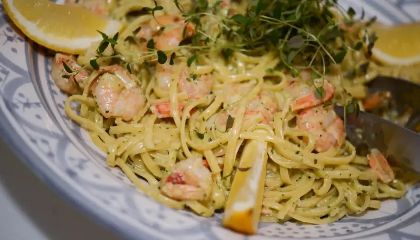En krämig pasta med scampi och spenat, garnerad med citronklyftor och färska örter. En härlig rätt som passar perfekt för en middag.