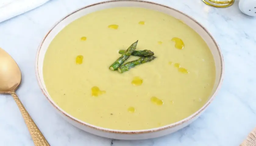 Deliciosa crema de esparragos trigueros, servida en un cuenco con un chorrito de aceite de oliva y espárragos frescos.