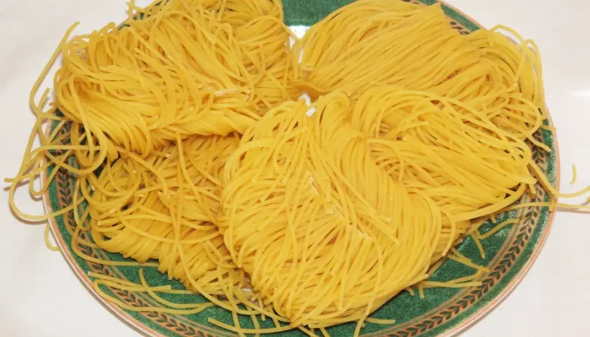 Na talerzu ułożone są kłębki cienkiego makaronu, gotowe do przygotowania pysznego dania. To idealne vermicelli po polsku!