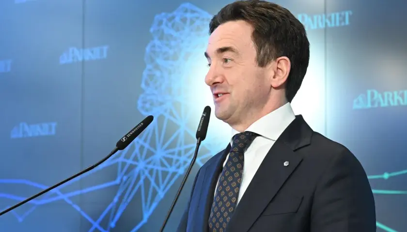 Mężczyzna w garniturze przemawia przy mikrofonach. Na ekranie w tle logo "Parkiet" i schemat sieci. Giełda Papierów Wartościowych (GPW) i bankierzy dyskutują o przyszłości.