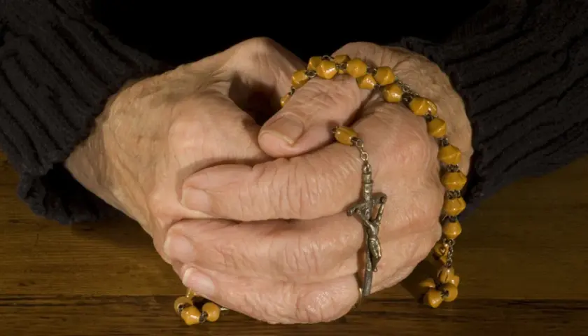 Dłonie trzymające różaniec, przygotowujące się do modlitwy do Ducha Świętego przed spowiedzią.