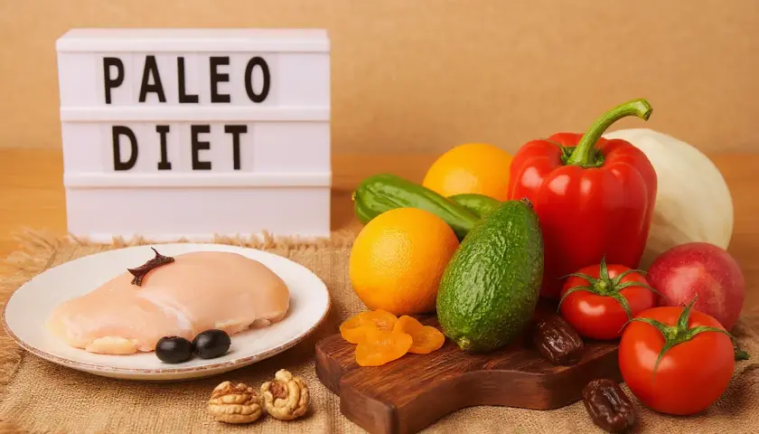 Dieta paleo co to? Na stole surowy kurczak, warzywa, owoce, orzechy i daktyle.
