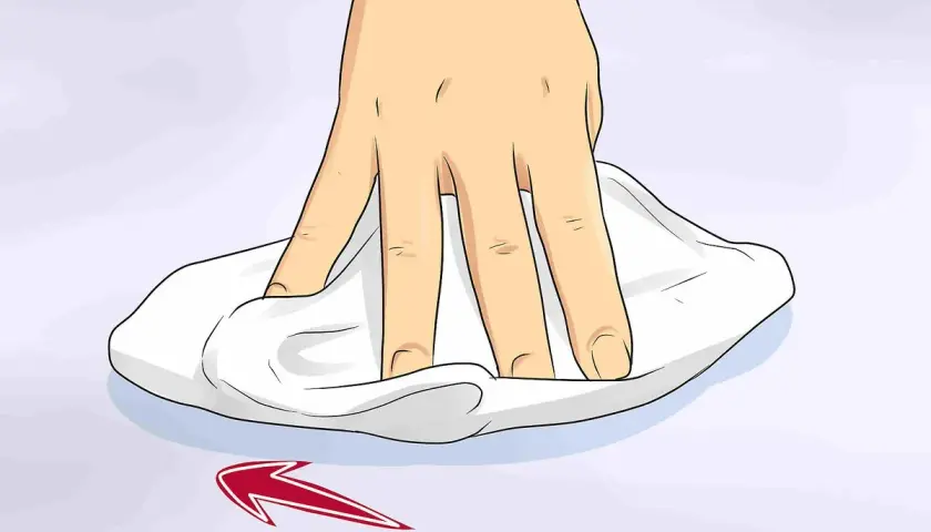Mano che pulisce una superficie con un panno bianco, mostrando come togliere graffi dal vetro con un movimento circolare.