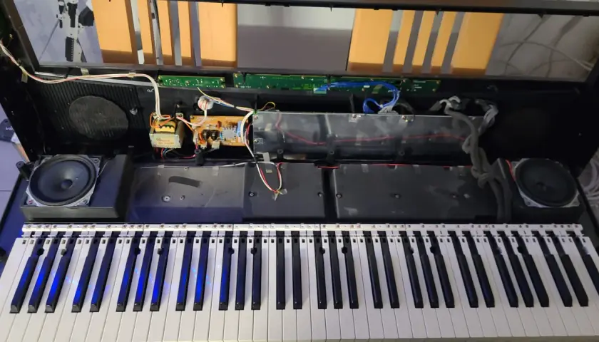 Wnętrze keyboardu podczas naprawy instrumentów muzycznych. Widoczne głośniki, płytki drukowane i okablowanie.