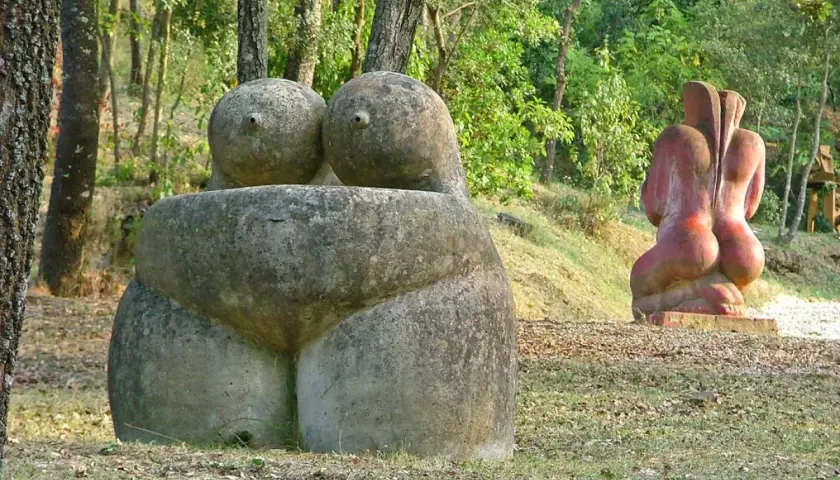 Esculturas de piedra en un museo al aire libre, evocando formas humanas en un entorno natural.