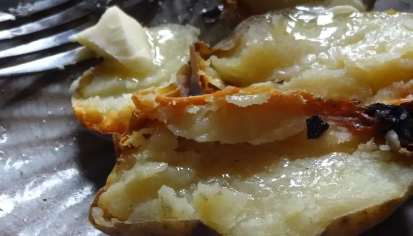 Pommes de terre cuites dans la cendre, ouvertes et garnies de beurre fondant. Un délice simple.
