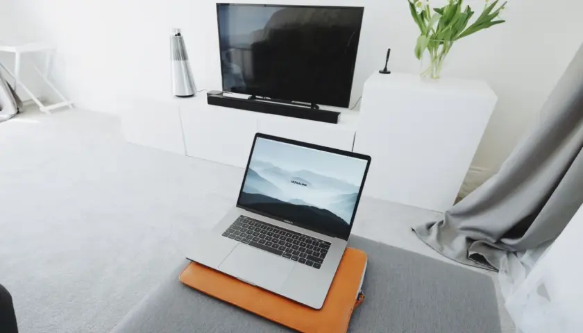 Nowoczesny salon z laptopem przygotowanym do screen mirroring na dużym ekranie telewizora.