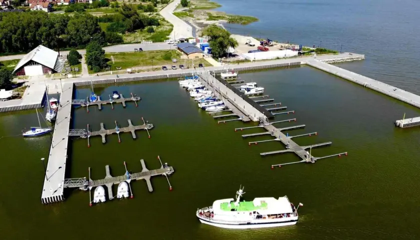 Widok z lotu ptaka na port w Krynicy Morskiej z licznymi łodziami i żaglówkami przy pomostach.