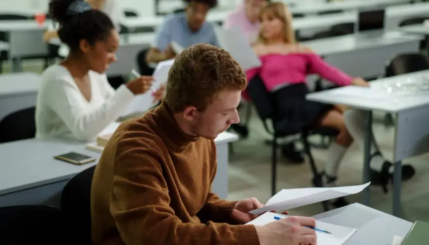 Studenci w sali wykładowej, skupieni na nauce. Nawet bez matury można rozpocząć studia, zdobywając wiedzę i nowe umiejętności.