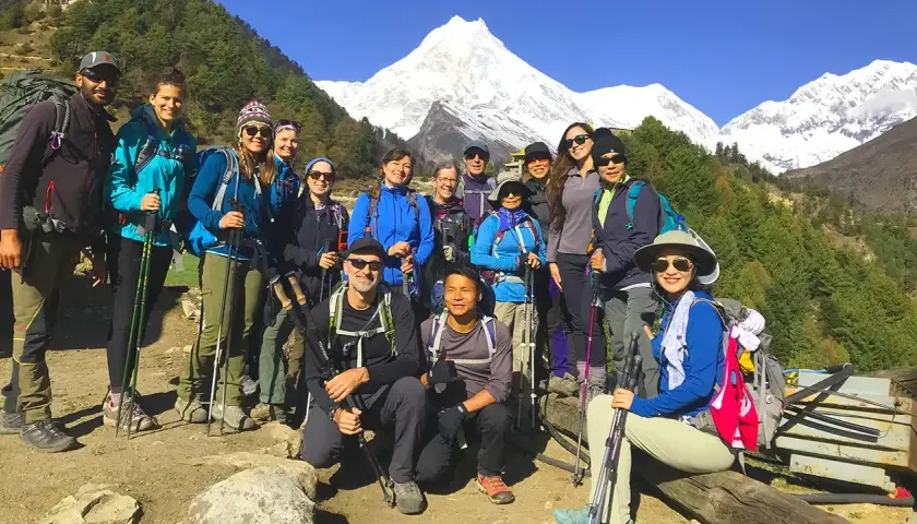 Grupa turystów na tle ośnieżonych gór podczas Manaslu Circuit Trek. Wszyscy uśmiechnięci, gotowi na przygodę.