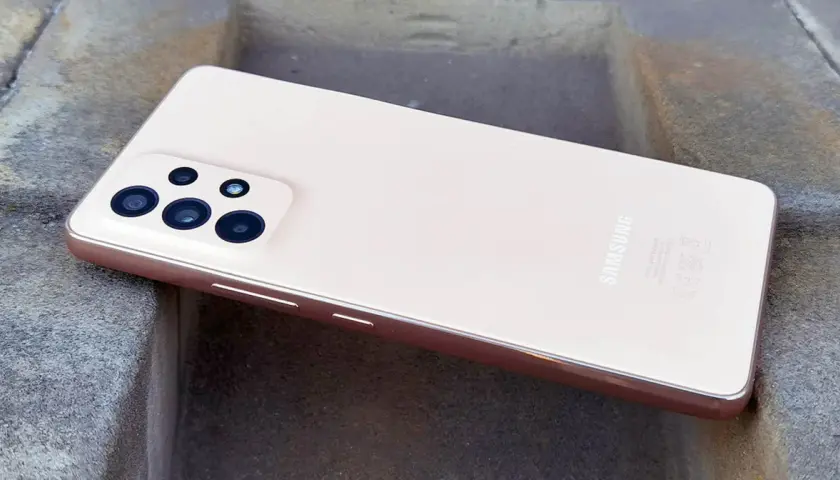 Różowy Samsung A53 z aparatem na kamiennym tle.