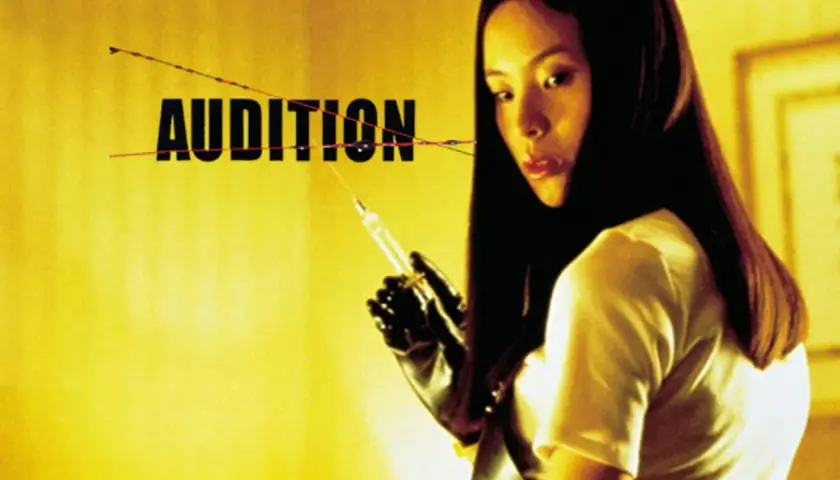 Mroczna scena z filmu "Audition" po polsku. Kobieta w rękawiczkach trzyma strzykawkę.