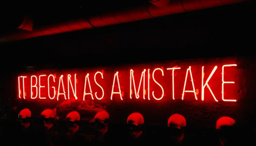 Neon rosso "IT BEGAN AS A MISTAKE" sopra teschi. Come si dice "lunedì" in inglese? Monday.