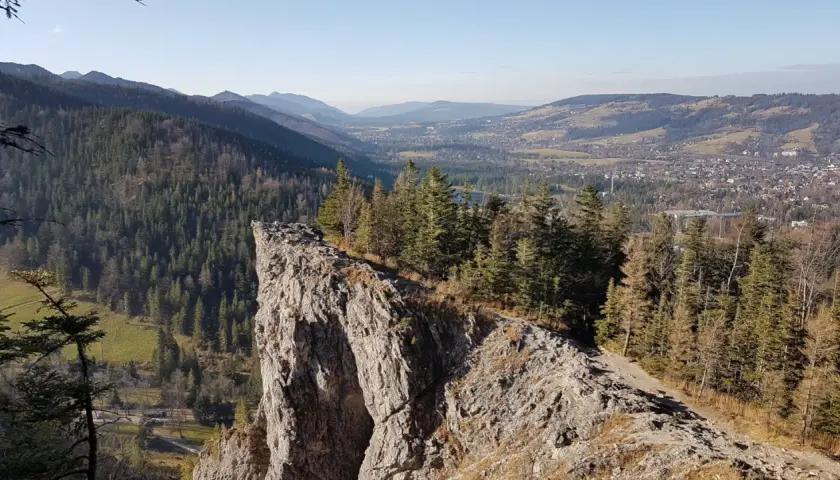 Widok z urwiska na Tatry i Zakopane. Ścieżka prowadzi przez las, pokazując, jak dojść na Nosal z Zakopanego.