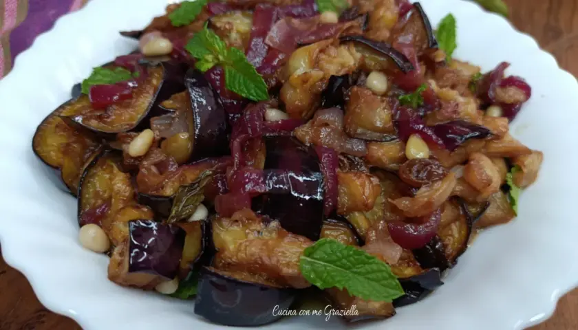 Melanzane in agrodolce, un piatto saporito con cipolle rosse, pinoli e menta fresca.