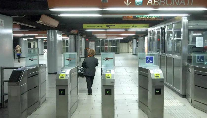 Ingresso della metropolitana di Roma con tornelli ATAC. Una donna attraversa i varchi per accedere ai binari.
