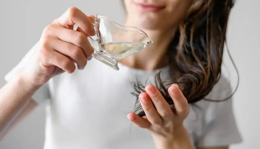 Kobieta aplikuje hydrolat na końcówki włosów. Hydrolat co to? To woda kwiatowa, która nawilża i odżywia włosy.