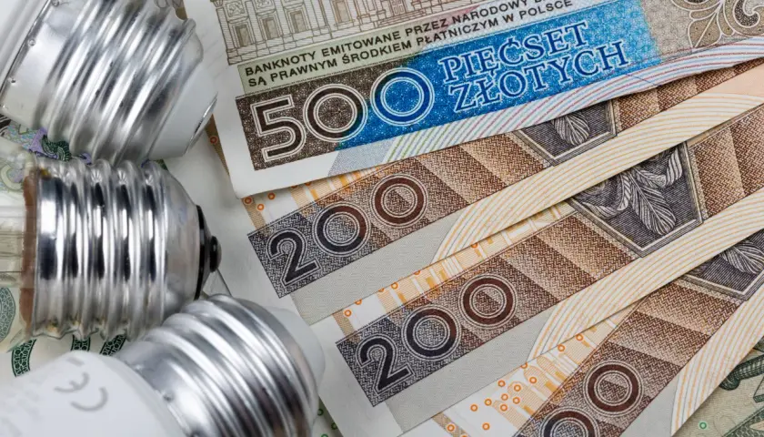 Żarówki na stosie banknotów 500 i 200 zł. Zastanawiasz się, ile kosztuje mwh prądu?